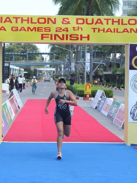 Jina crossing the finish line under the 24th SEA Games Thailand triathlon finish banner, 2007